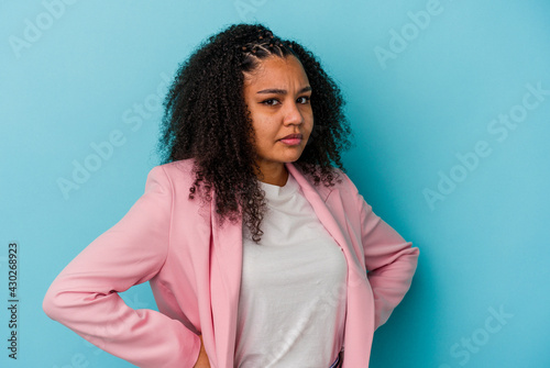 Young african american woman isolated on blue background frowning face in displeasure, keeps arms folded.