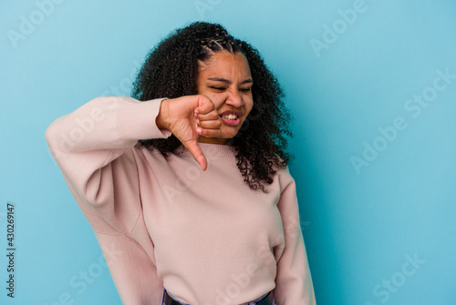 Young african american woman isolated on blue background showing thumb down and expressing dislike.