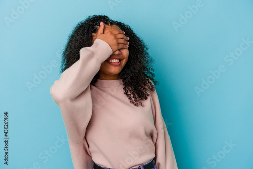 Young african american woman isolated on blue background laughs joyfully keeping hands on head. Happiness concept.