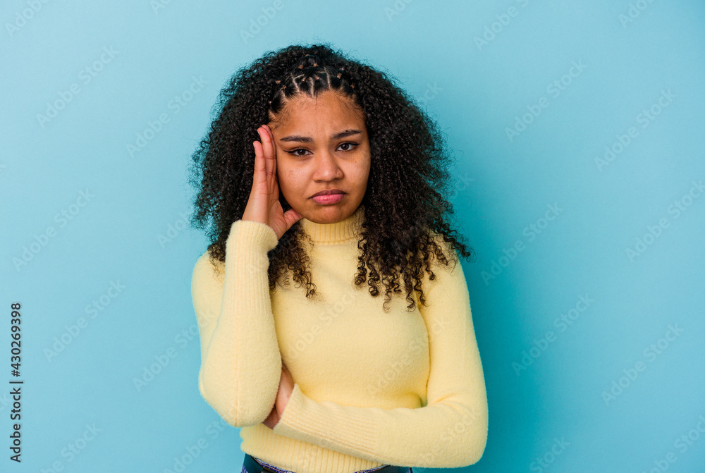 Young african american woman isolated on blue background blows cheeks, has tired expression. Facial expression concept. Young african american woman isolated on blue background blows cheeks, has tired expression. Facial expression concept.