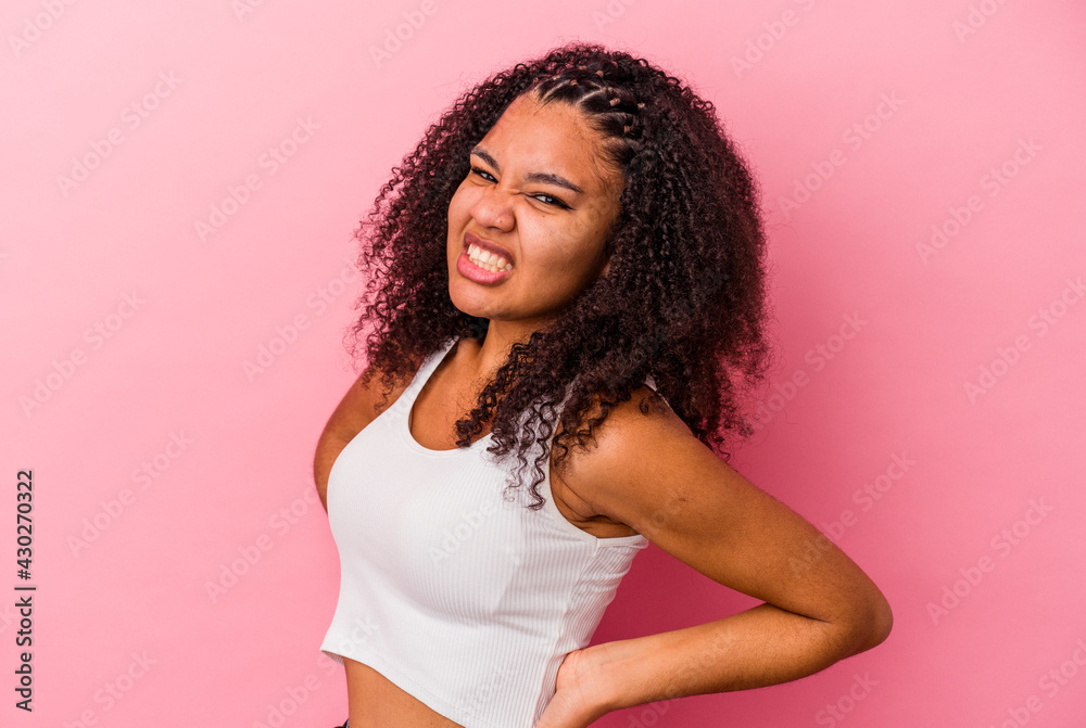 Young african american woman isolated on pink background suffering a back pain. Young african american woman isolated on pink background suffering a back pain.