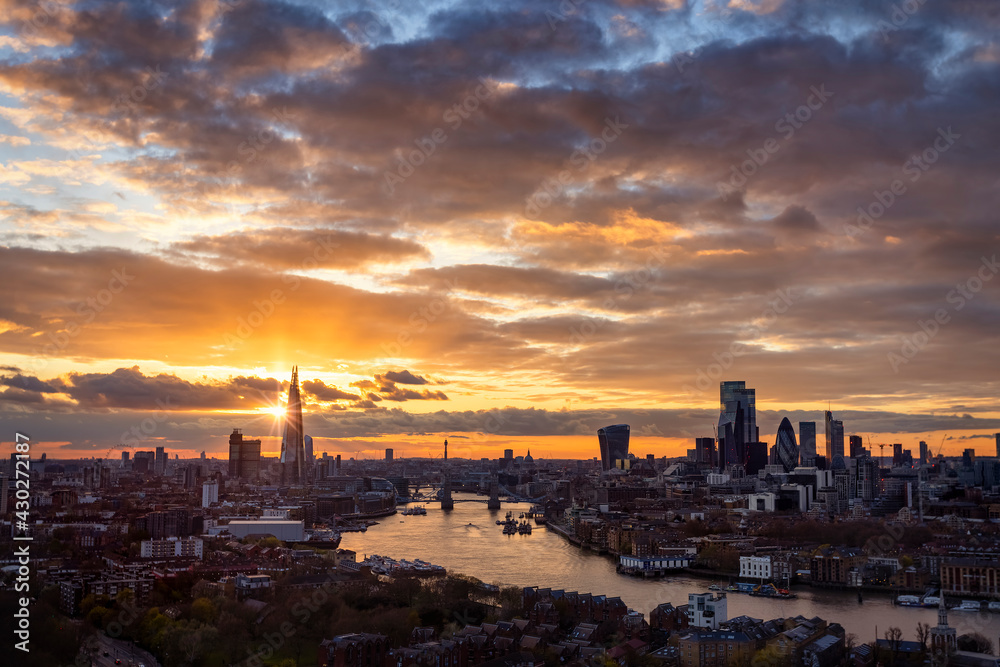 The urban skyline of London, United Kingdom, with Tower Bridge, Thames river and City district during a cloudy sunset