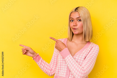Young venezuelan woman isolated on yellow background shocked pointing with index fingers to a copy space.
