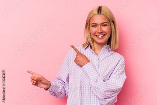 Young venezuelan woman isolated on pink background pointing with forefingers to a copy space, expressing excitement and desire.