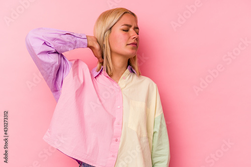 Young venezuelan woman isolated on pink background having a neck pain due to stress, massaging and touching it with hand.