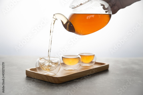 The hot tea is poured into a transparent cup on a white background.