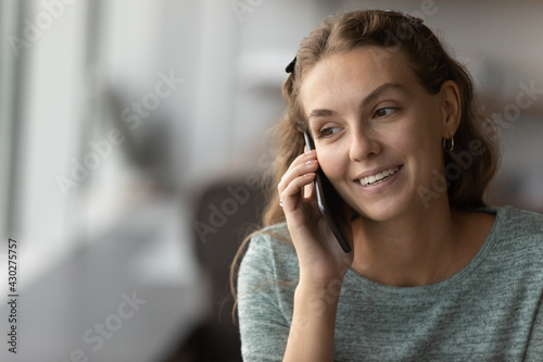 Crop close up of smiling Caucasian female employee hold cellphone gadget talk speak online with client or customer. Happy woman have pleasant smartphone communication with partner or colleague.