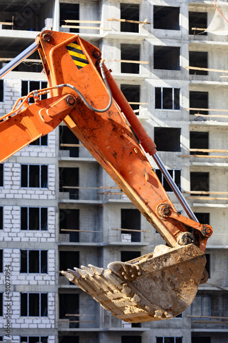 Excavator bucket against the wall of a residential building on the construction site