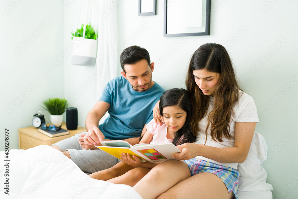 Parents reading to their kid before sleeping Parents reading to their kid before sleeping