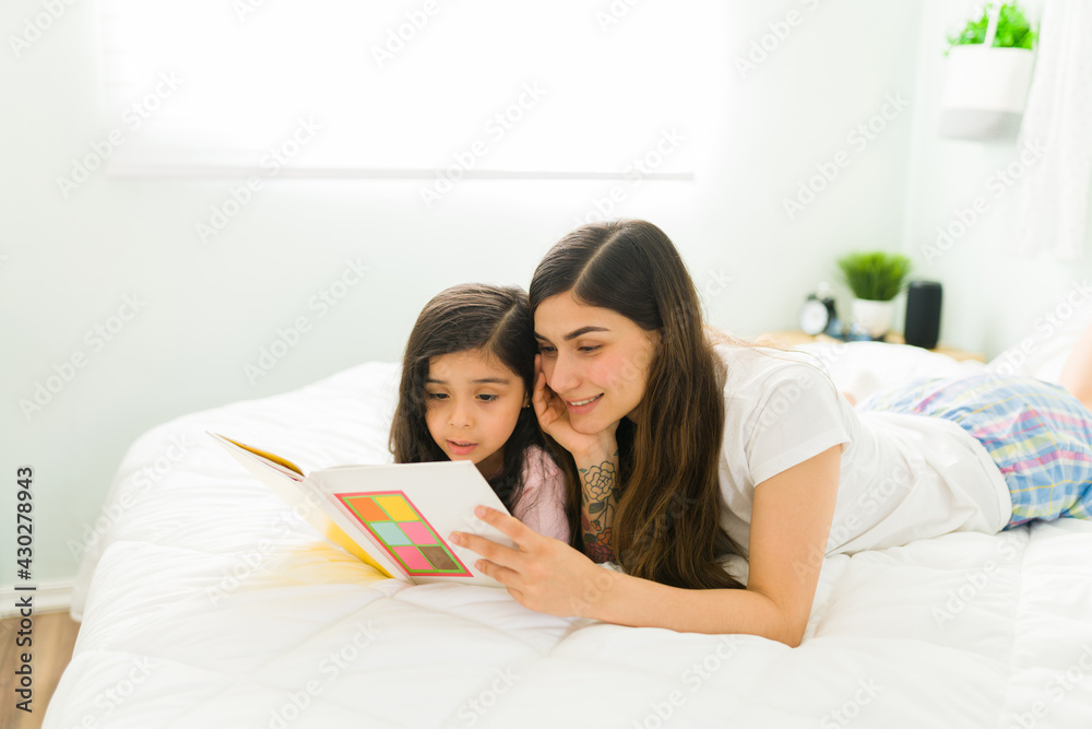 Young mom admiring her daughter reading skills Young mom admiring her daughter reading skills