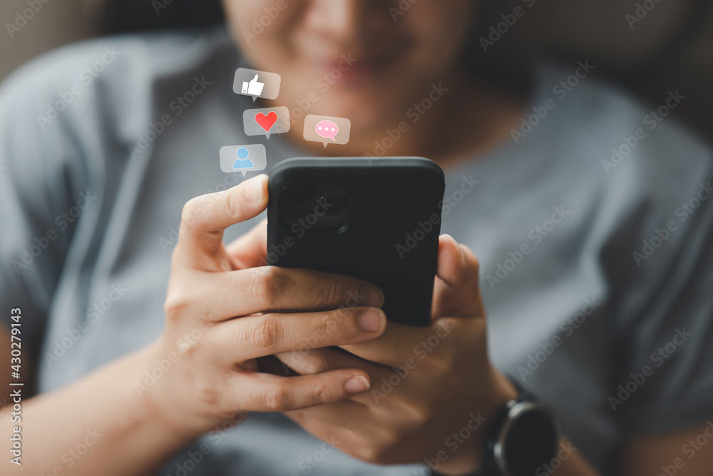 Social media interactions on mobile phone, concept with notification icons of social media above smartphone screen, person hands holding device, internet digital marketing - obrazy, fototapety, plakaty 