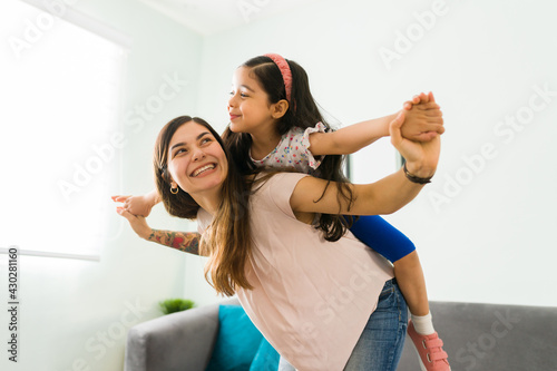 фотографія Latin mother having fun with her daughter and pretending to fly