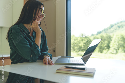 Side view of business woman working from home with laptop and notebook