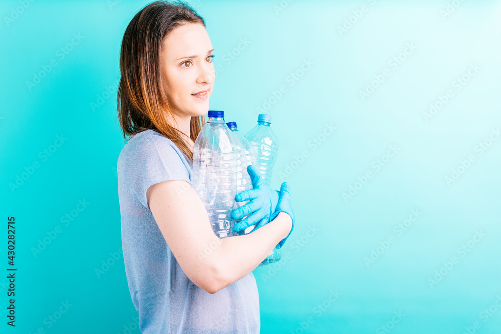 beautiful young woman holding plastic bottles on blue background. recycling concept. environmental care beautiful young woman holding plastic bottles on blue background. recycling concept. environmental care