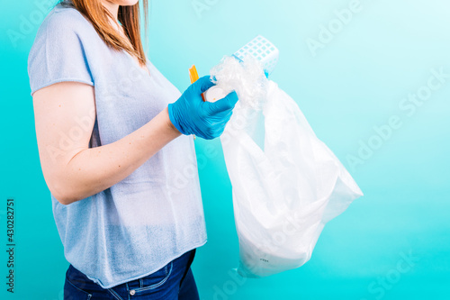 adult young woman recycling plastic bottles on blue background. recycling concept. plastic free
