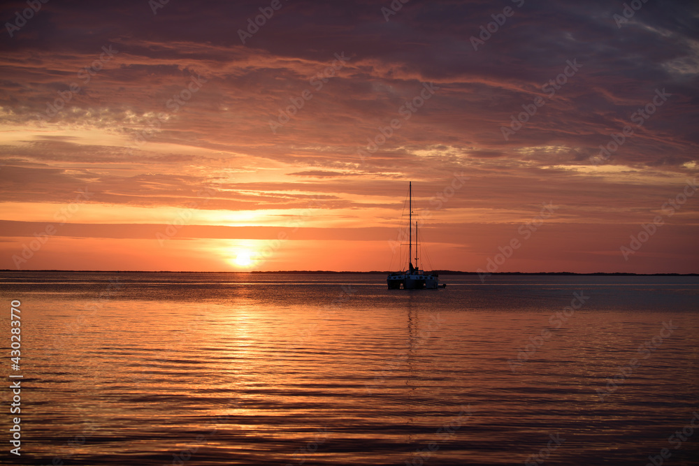 Sailboats at sunset. Ocean yacht sailing along water. Boat on the sea.