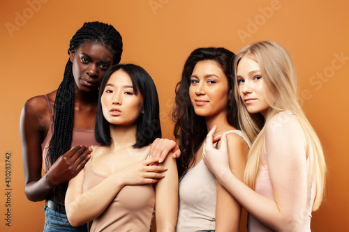 young pretty asian, caucasian, afro woman posing cheerful together on brown background, lifestyle diverse nationality people concept