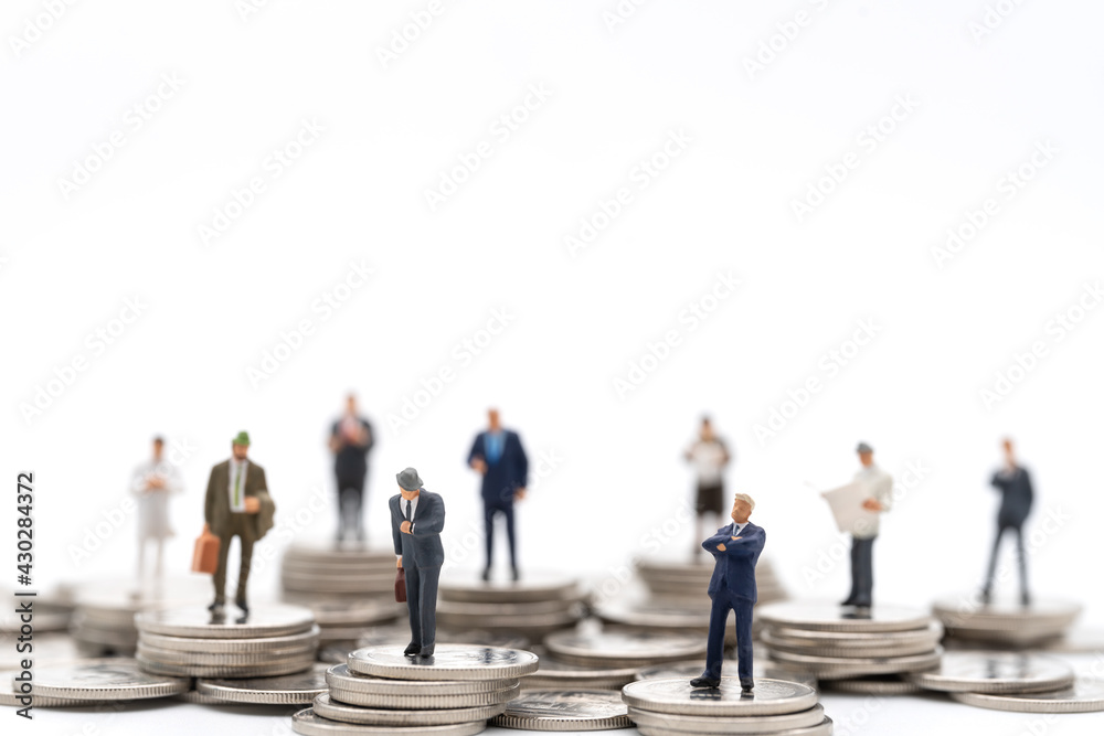 Business amd Money Concept. Group of businessman miniature figures people standing on stack of silver coin on white background.
