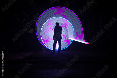 One person standing alone against a Colourful circle light painting as the backdrop 