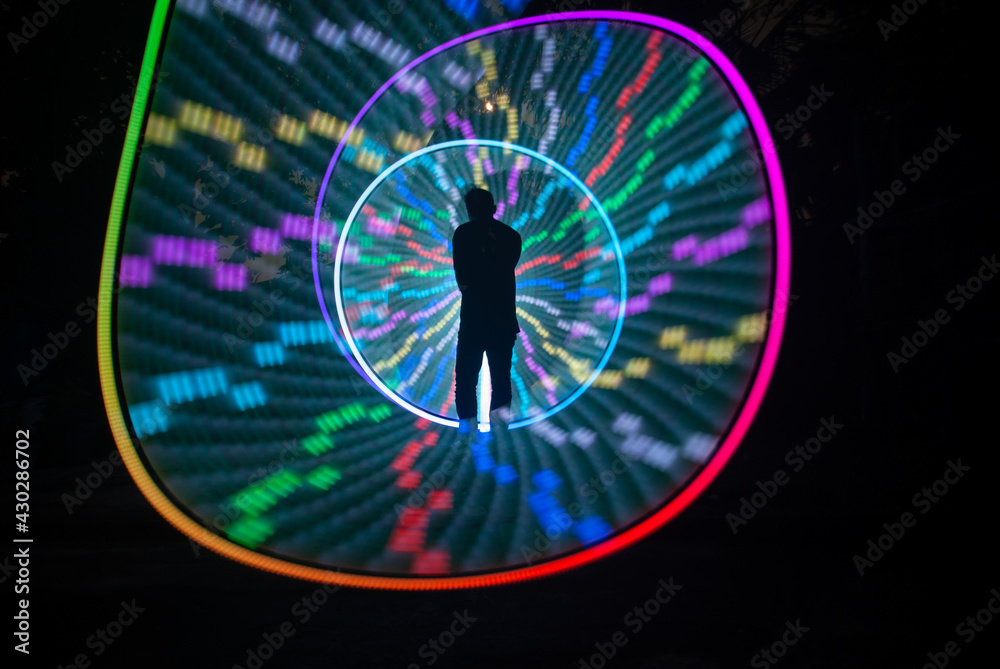 One person standing alone against a Colourful circle light painting as the backdrop One person standing alone against a Colourful circle light painting as the backdrop