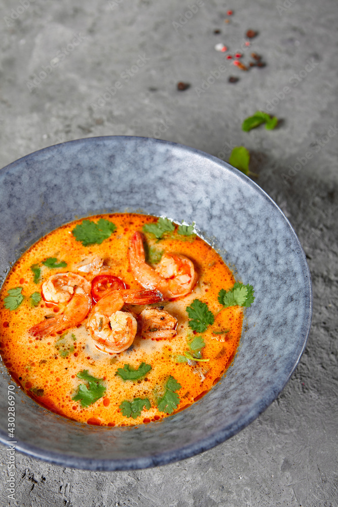 Tom Yum or Tom Yam Soup - Hot and Sour Thai Soup cooked with Shrimp. Thai Authentic Traditional Dinner. Soup in Blue Bowl on Dark Grey Table. Street Asian Food. Tom Yum or Tom Yam Soup - Hot and Sour Thai Soup cooked with Shrimp. Thai Authentic Traditional Dinner. Soup in Blue Bowl on Dark Grey Table. Street Asian Food.