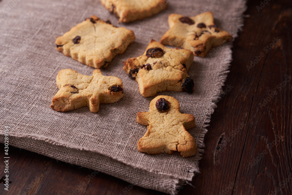 Healthy homemade gluten-free, lactose-free cookies of various shapes without sugar with raisins and chocolate on a dark brown wooden background Healthy homemade gluten-free, lactose-free cookies of various shapes without sugar with raisins and chocolate on a dark brown wooden background