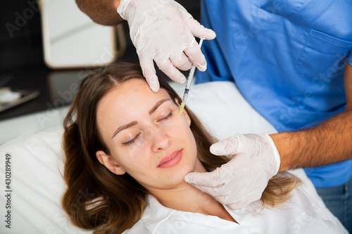 Young woman getting procedure of injection contouring for facial correction in aesthetic cosmetology clinic .