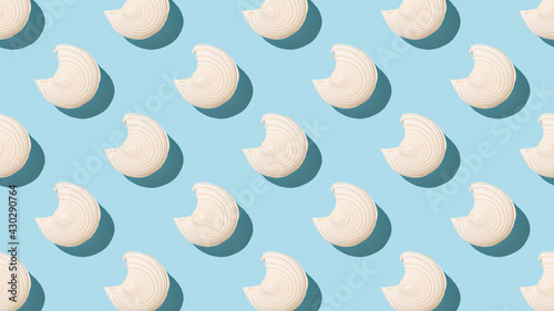 A pattern of bitten fresh meringue on a blue background.