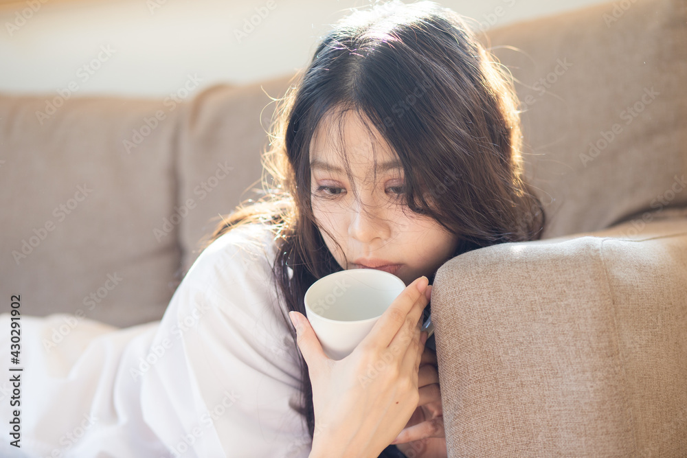Pretty women with coffee cup lying on sofa light of window Pretty women with coffee cup lying on sofa light of window