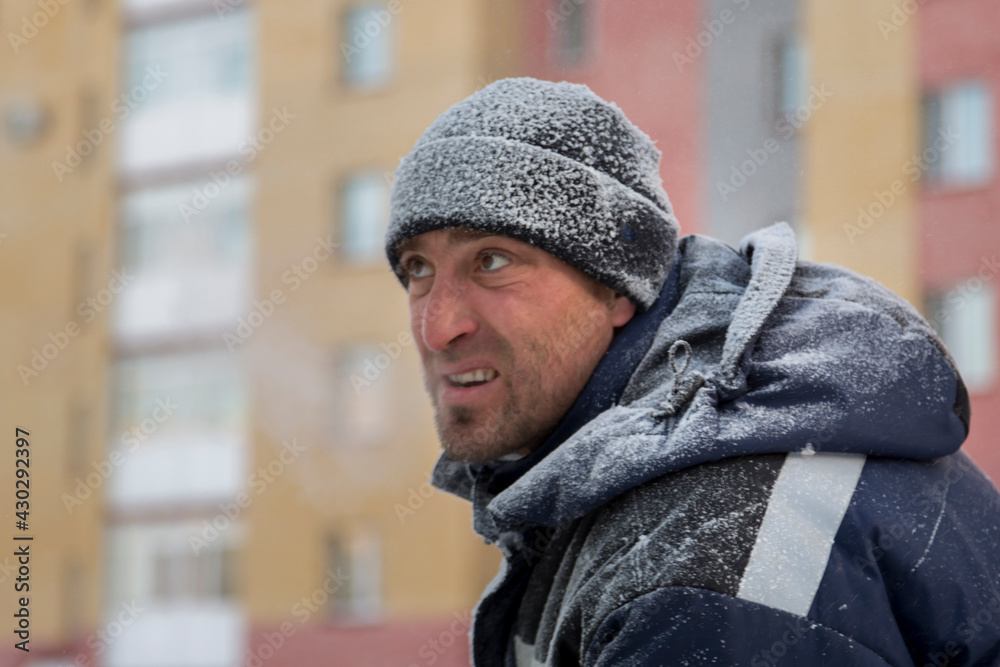 Portrait of a worker in a blue jacket with a hood at a construction site Portrait of a worker in a blue jacket with a hood at a construction site