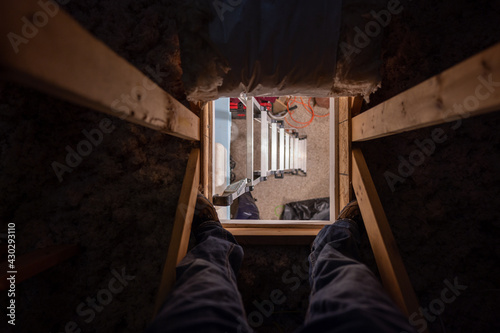 Looking down through the access opening to an attic with the ladder underneath
