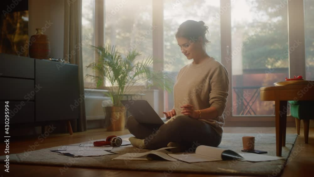 Young Woman Using Laptop at Home, Does Remote Work. Beautiful Smiling Girl Sitting on the Floor Works with Papers, Documents, Brainstorms Project with Research. Productive Work in Sunny Living Room