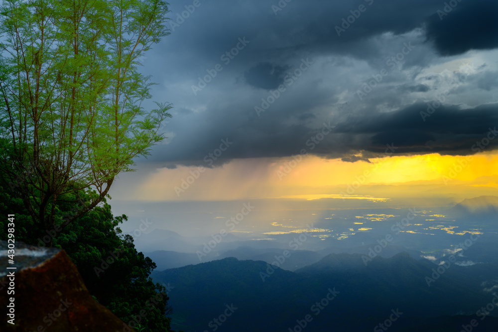 Rain and the dark clouds in the distance view from a mountain top, evening sunset, and dramatic heavy thunderstorm clouds side view.