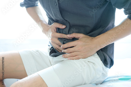 Young man uses his hands to hold his stomach and has a severe stomachache.on isolated white background © Photo Sesaon