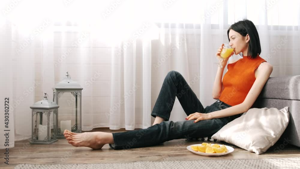 Young woman sitting on the flor with orange juice Young woman sitting on the flor with orange juice