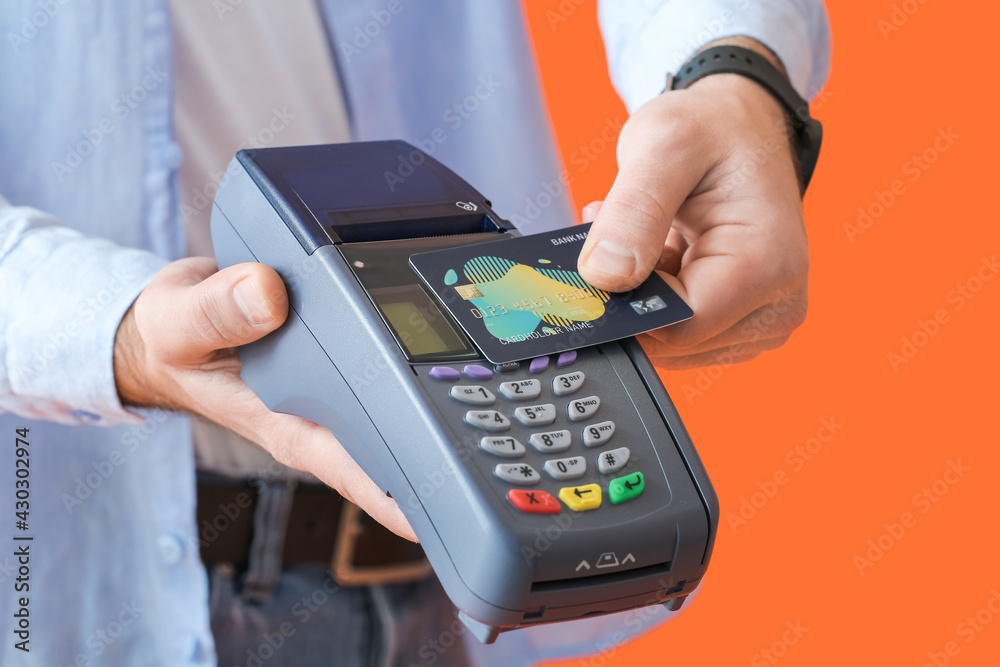 Man with payment terminal and credit card on color background, closeup Man with payment terminal and credit card on color background, closeup