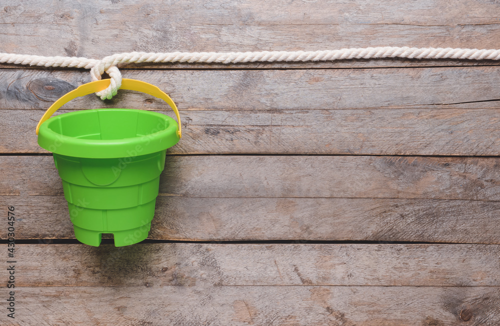 Toy bucket for children with rope on wooden background Toy bucket for children with rope on wooden background