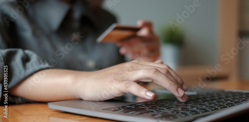woman hand holding credit card with using laptop for online shopping while making orders at home. business, lifestyle, technology, ecommerce, digital banking and online payment concept.