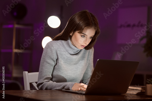 Young woman using laptop late at night. Addiction concept