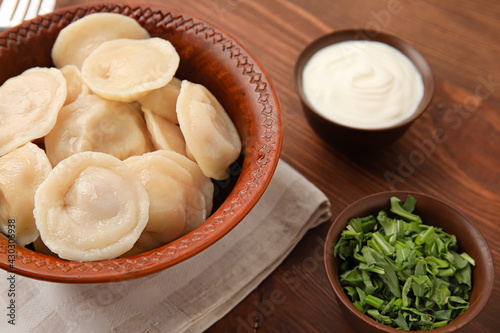 Bowl with tasty dumplings on wooden background