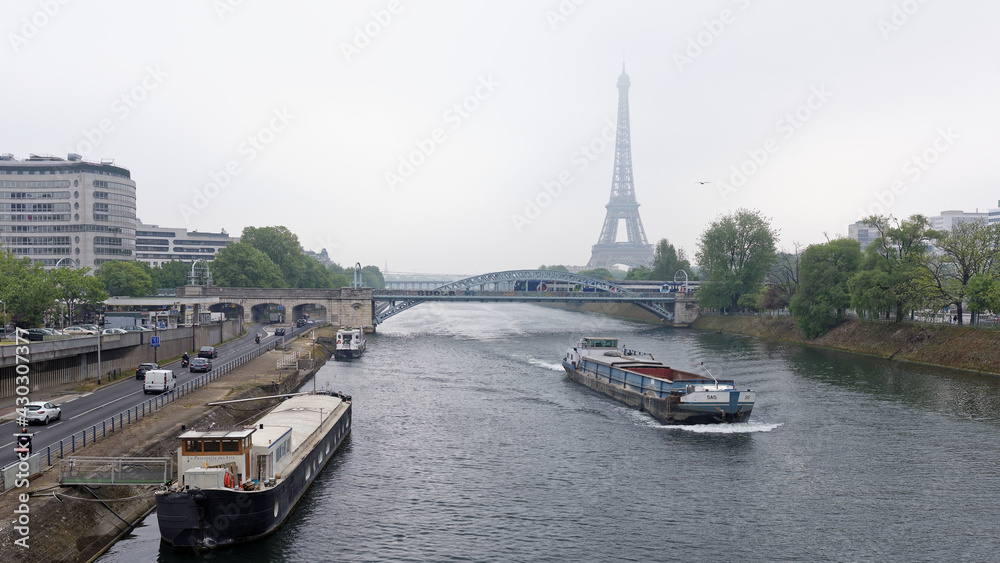 Fototapeta premium View of the Grenelle Bridge. On the embankment are moving cars and pedestrians, along the river-ship