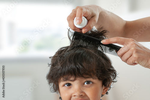 Mother treating daughter's hair against lice. Head lice treatment for schoolchild. photo