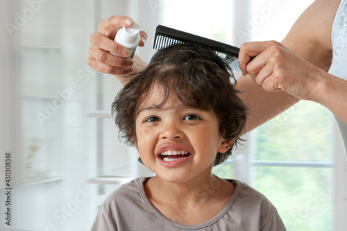 Mother treating daughter's hair against lice. Head lice treatment for schoolchild. photo