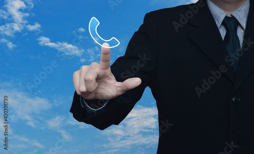 Businessman pressing telephone flat icon over blue sky with white clouds, Business contact us, Customer service and support concept © grapestock