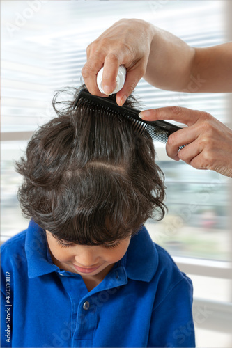 Mother treating daughter's hair against lice. Head lice treatment for schoolchild.