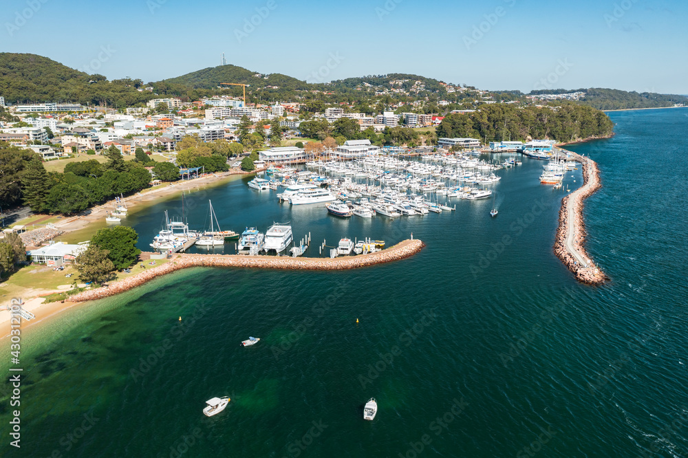 Aerial view of Nelson Bay marina, breakwater, town, and aqua waters of Port Stephens, Australia.