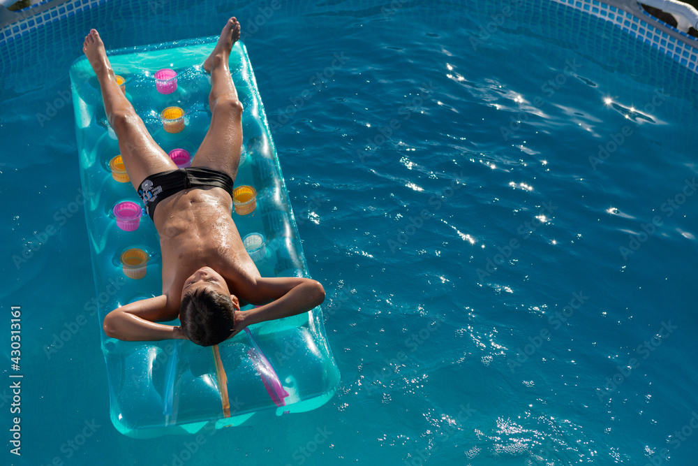 teen boy in the pool floats on an inflatable mattress top view