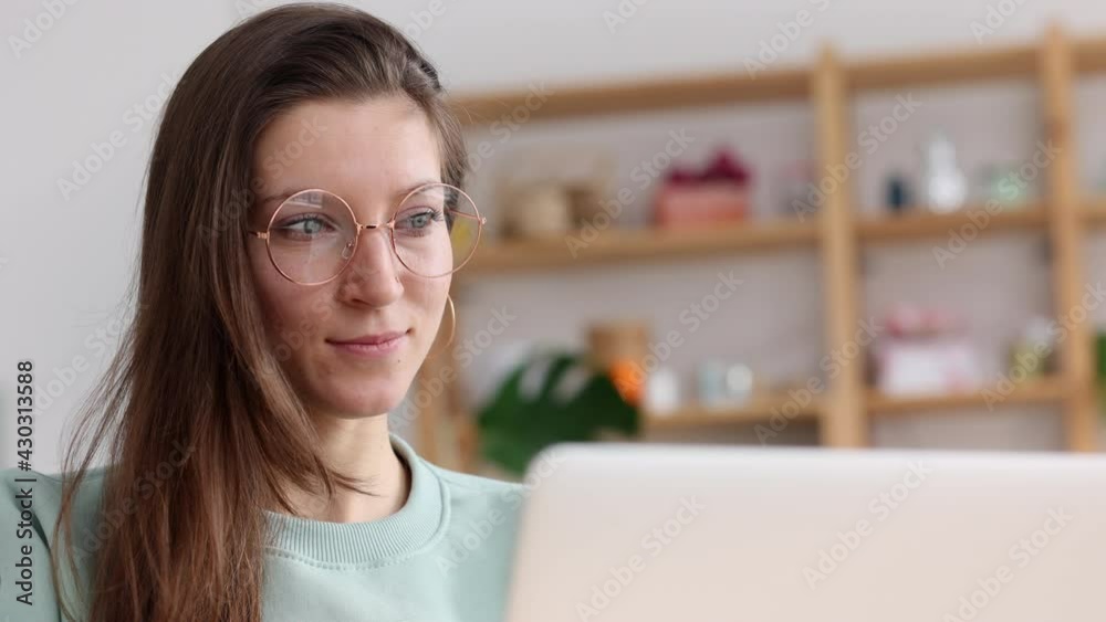 Businesswoman using laptop and laughing while sitting at desk in apartment interior spbi.