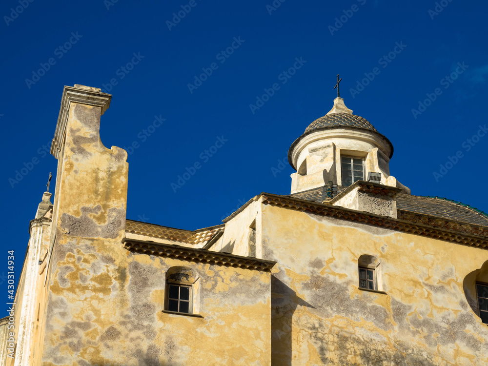 View of the bell tower of the Saint Jean Baptiste Calvi Cathedral. The Roman Catholic Church in the center of the high and ancient citadel of Calvi. Corsica, France.