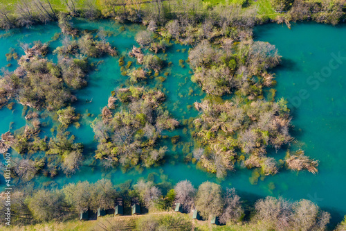 Croatia, Mreznica river from drone, overhead shot of waterfalls and trees in spring. Small wooden tents on shore.